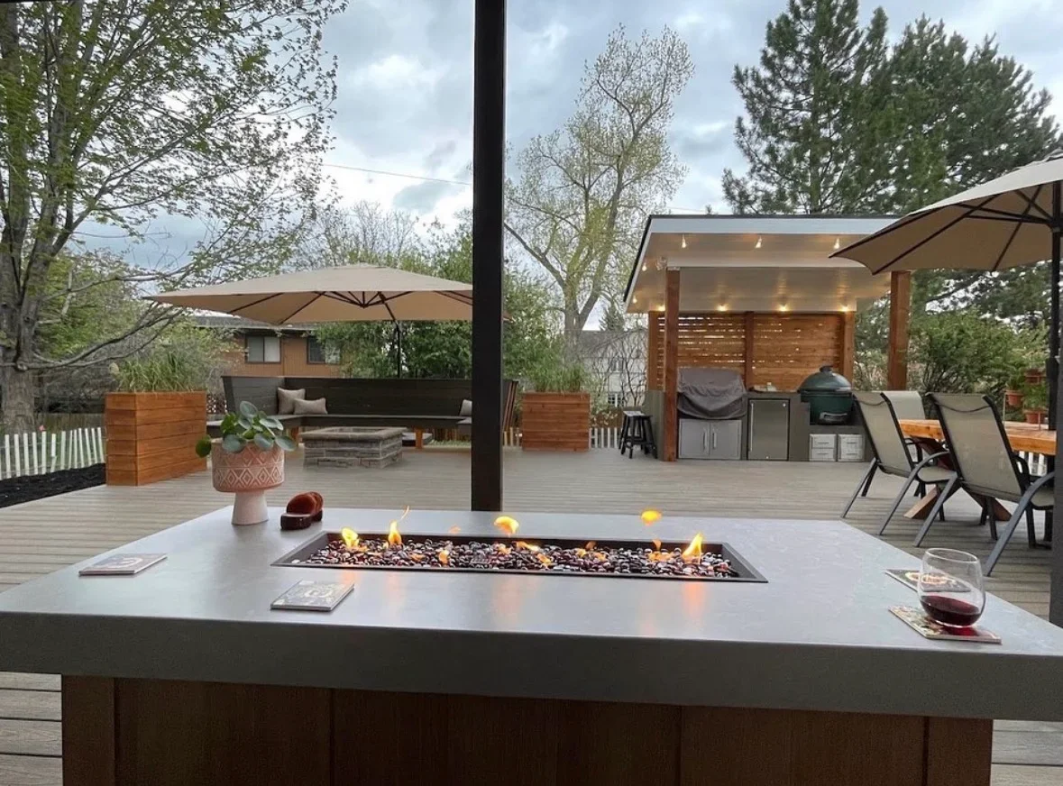 Composite deck with built-in fire table, covered patio with outdoor kitchen, lounge seating, and umbrellas