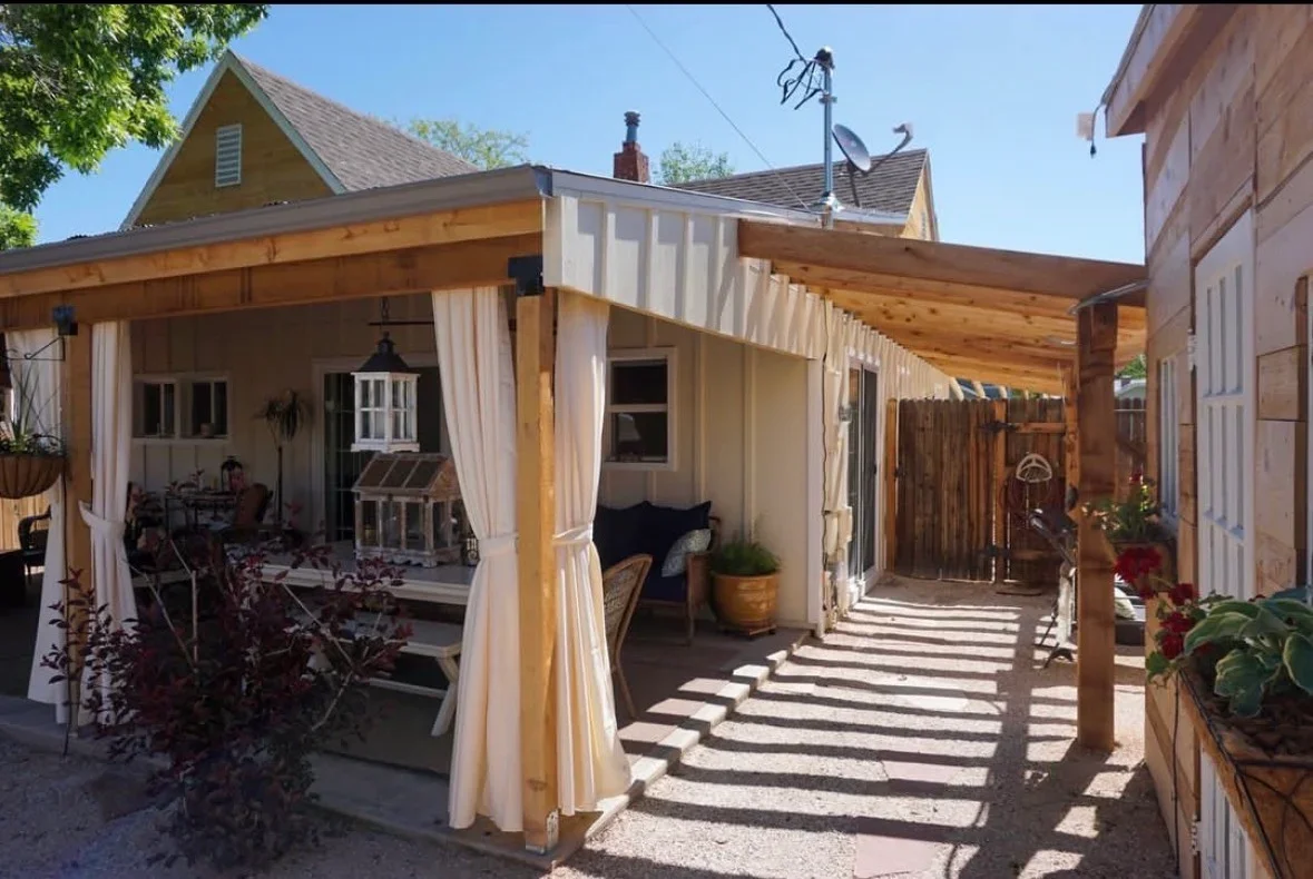Cedar pergola with cream curtains, concrete pavers, and integrated outdoor seating area