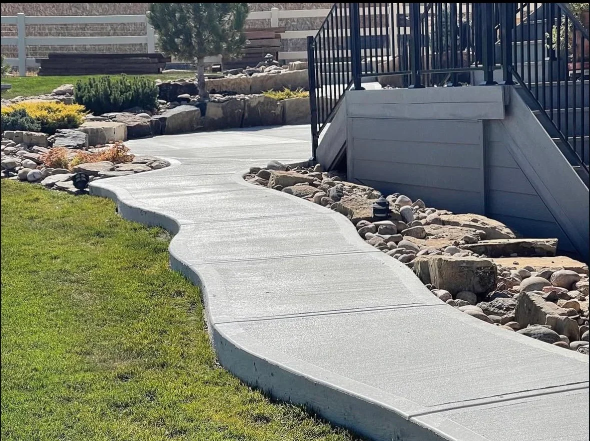 Curved concrete walkway with river rock edging and control joints