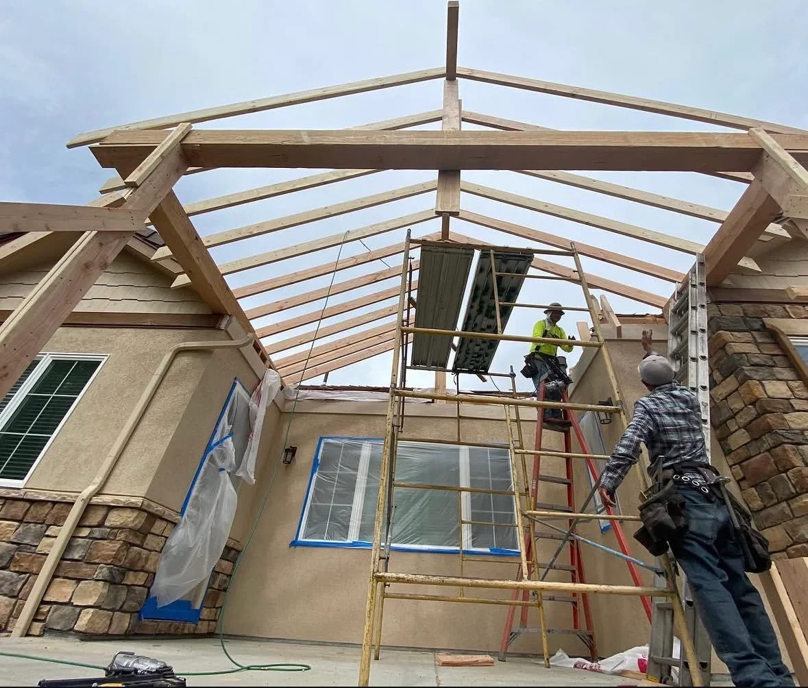 Timber pergola with gable roof framing over patio, stone and stucco home exterior