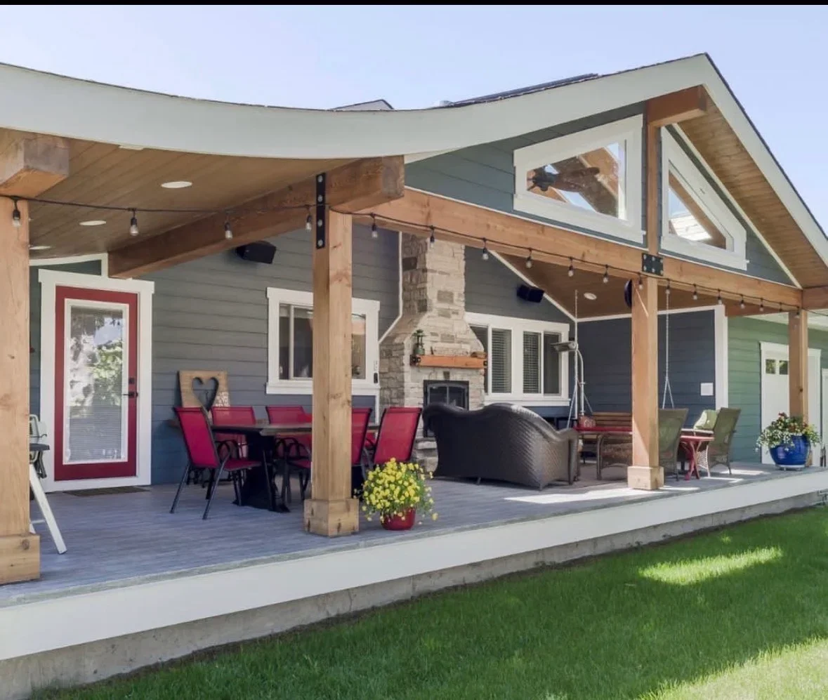 Composite deck with timber-framed patio cover, stone fireplace, and recessed lighting