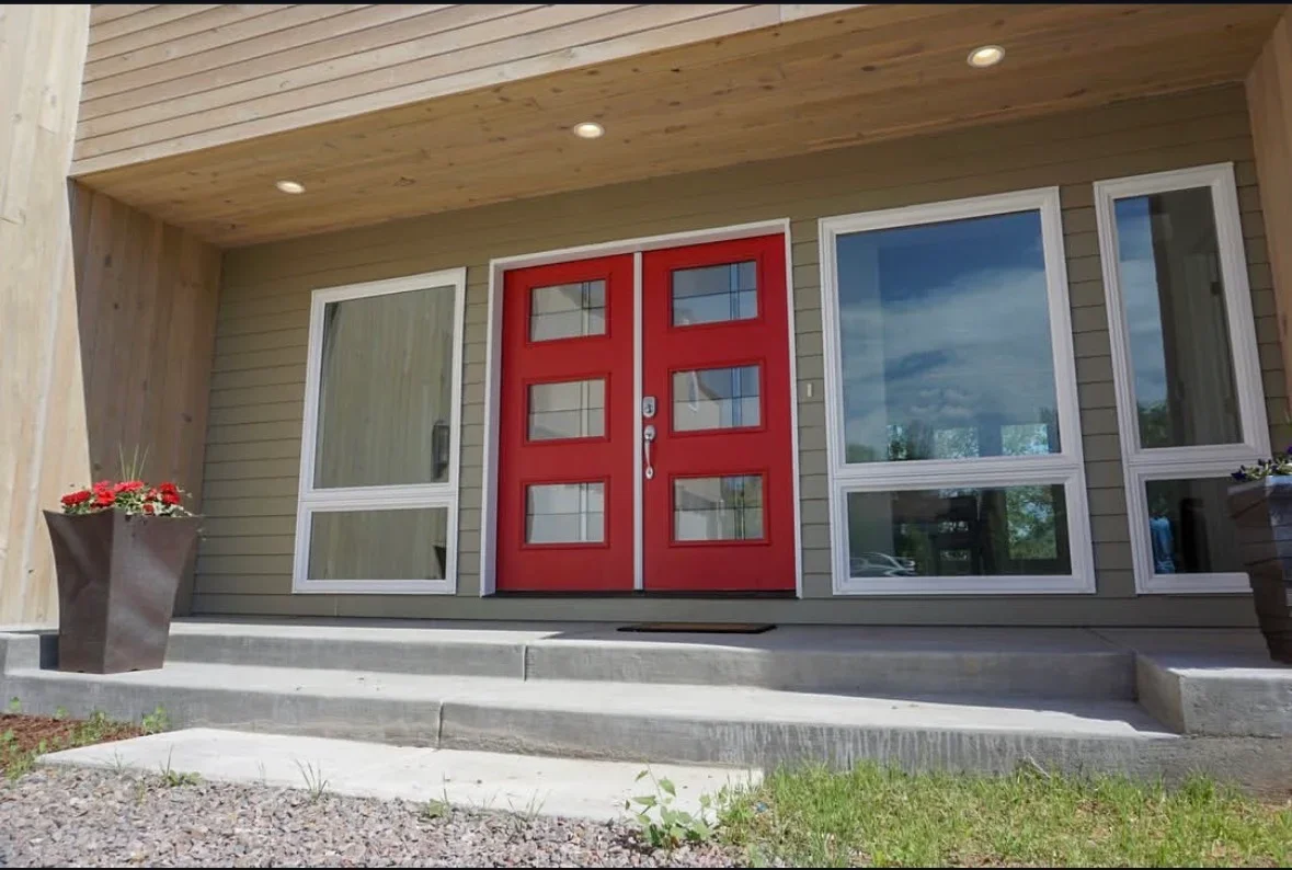 Concrete entry steps and platform with finished treads leading to red entry doors