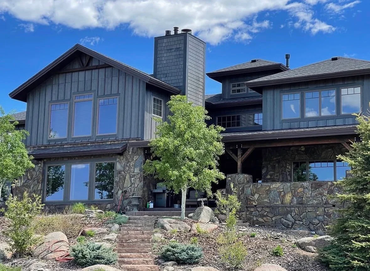 Modern home exterior with stacked stone veneer, gray metal siding, and large windows