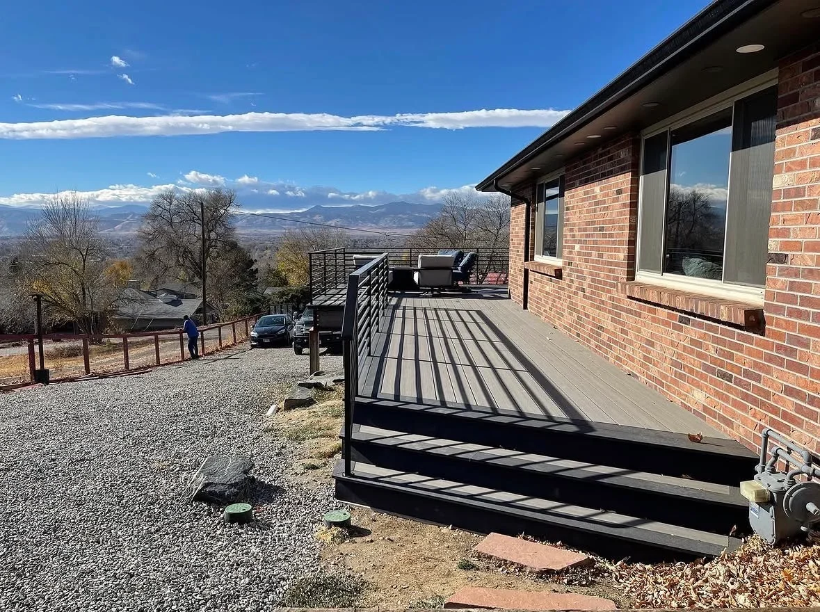 Gray composite deck with black metal railing and steps overlooking mountain landscape