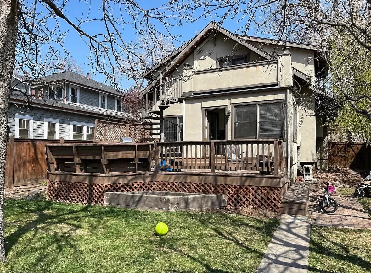 Multi-level composite deck with lattice skirting, railings, and bench seating attached to residential home
