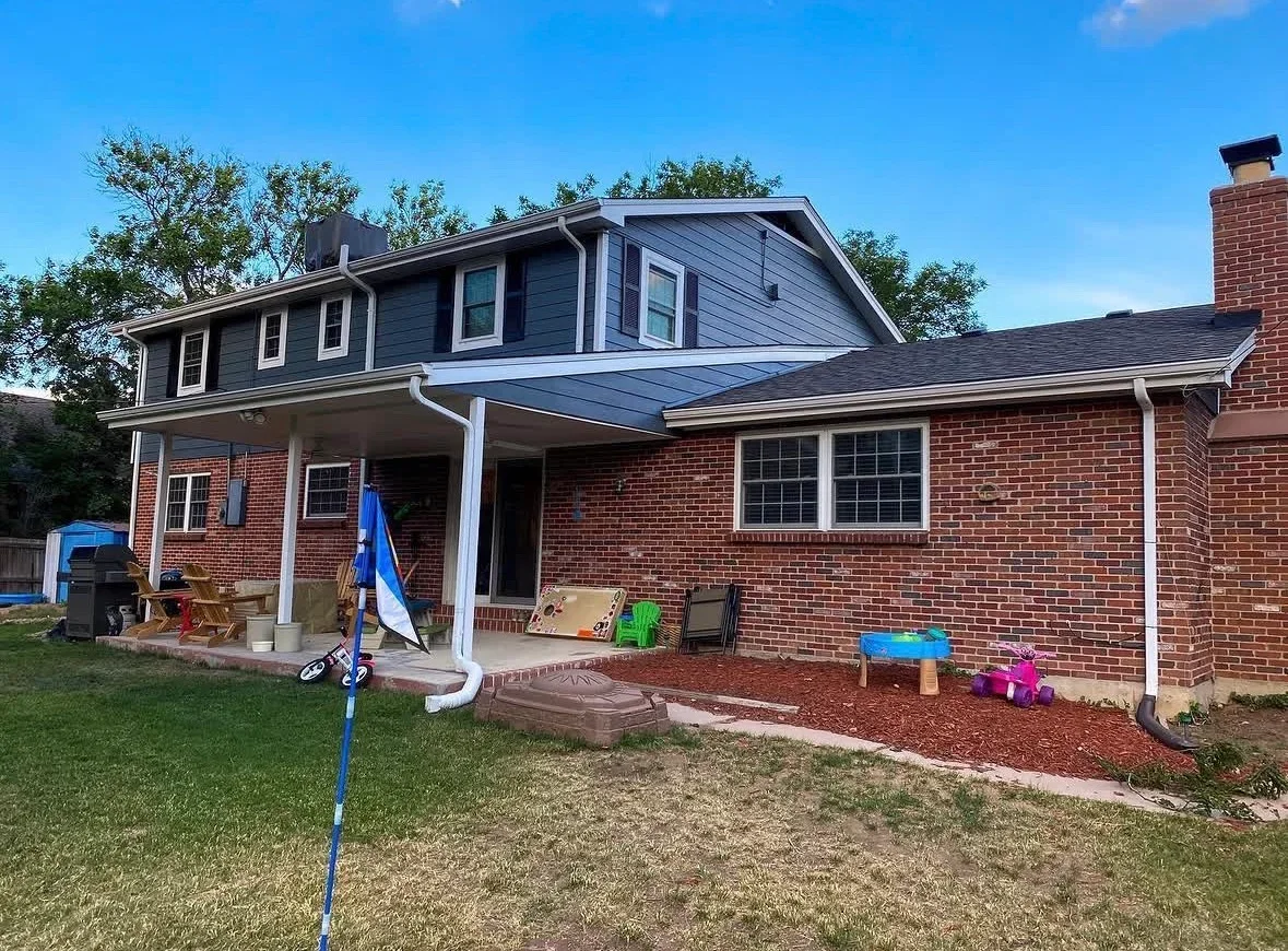 Covered patio with white posts, composite decking, and sloped roof attached to brick home