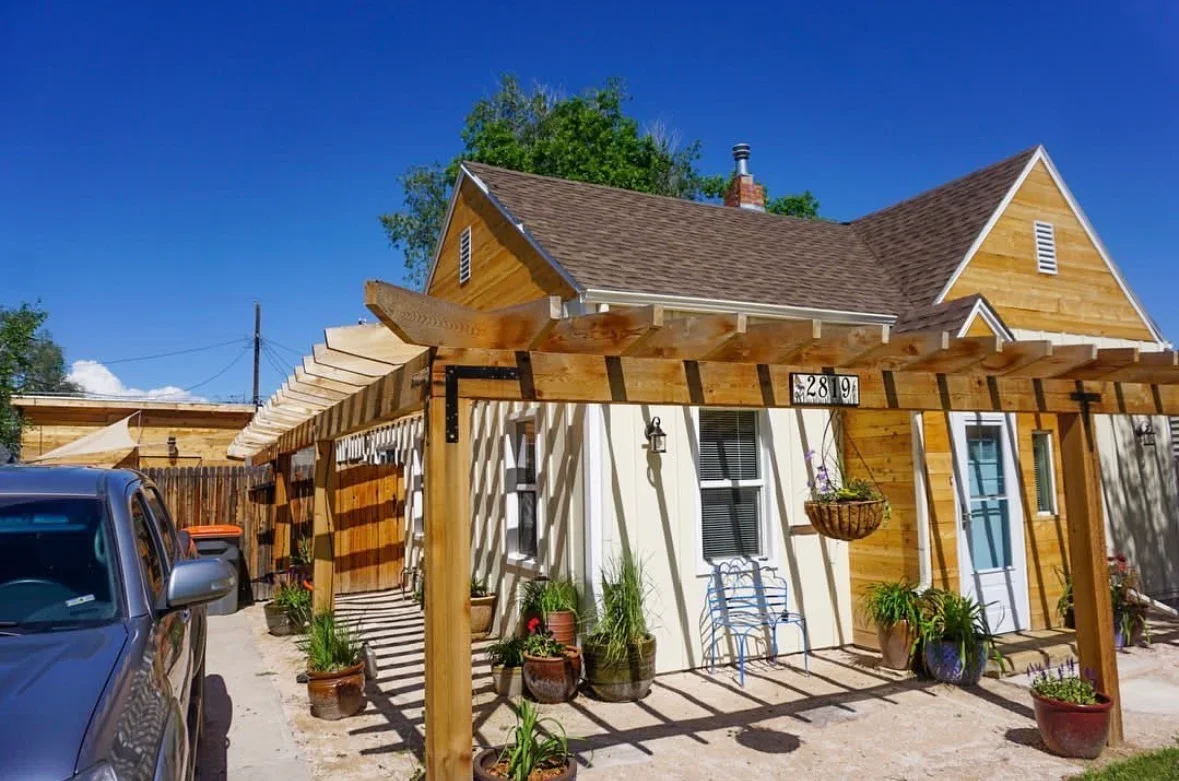 Wooden pergola with shade panels over patio, exposed beams and horizontal slats