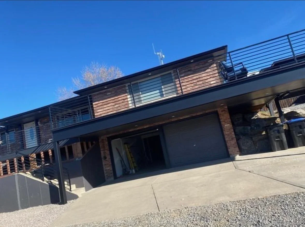 Horizontal wood deck with metal cable railings and concrete patio foundation on modern home