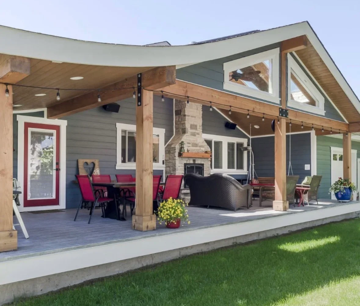 Composite deck with wooden pergola, concrete patio, stone fireplace, and integrated outdoor seating areas