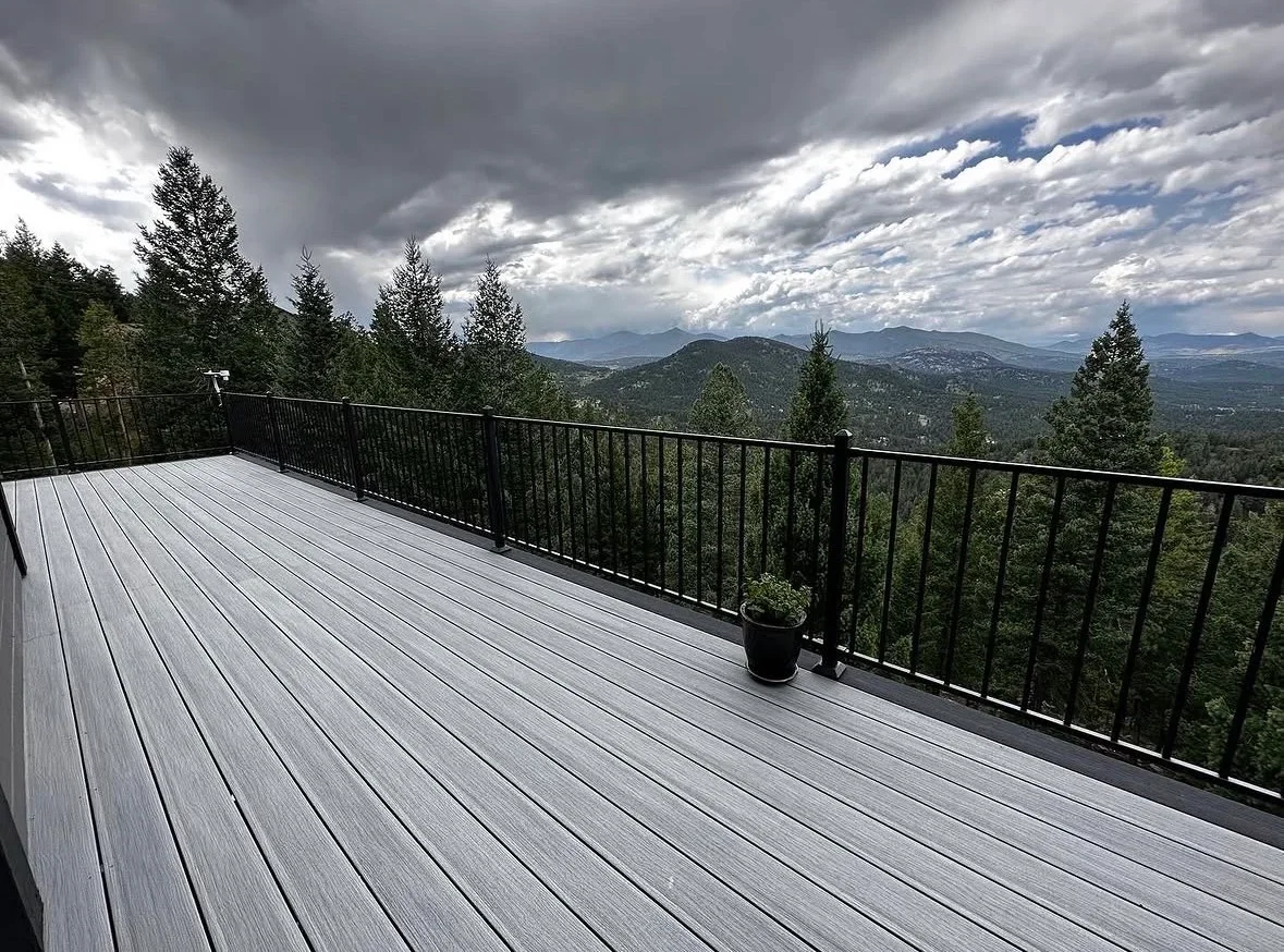 Gray composite deck with black metal railing overlooking mountain forest landscape