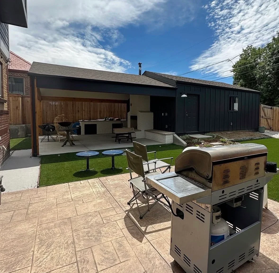 Stamped concrete patio with covered structure, outdoor kitchen, and lawn seating area