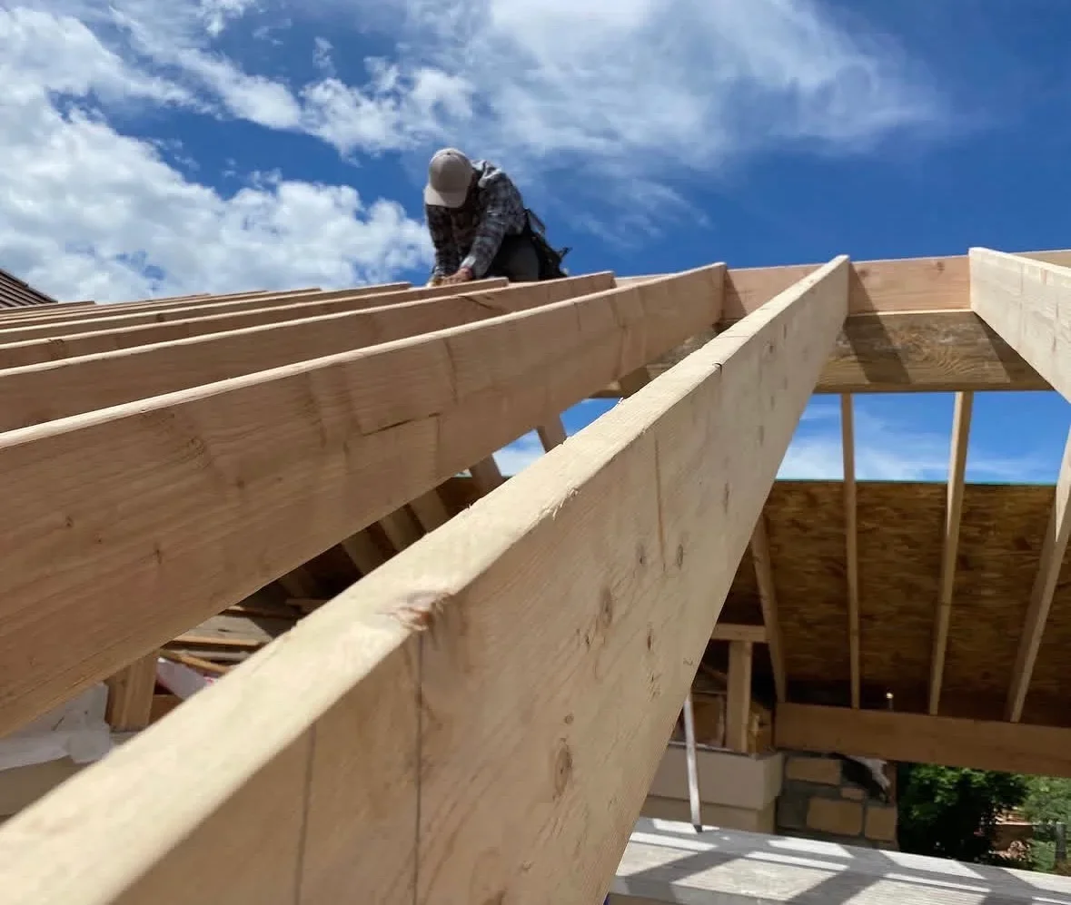 Carpenter installing wooden roof beams and rafters on residential structure framing