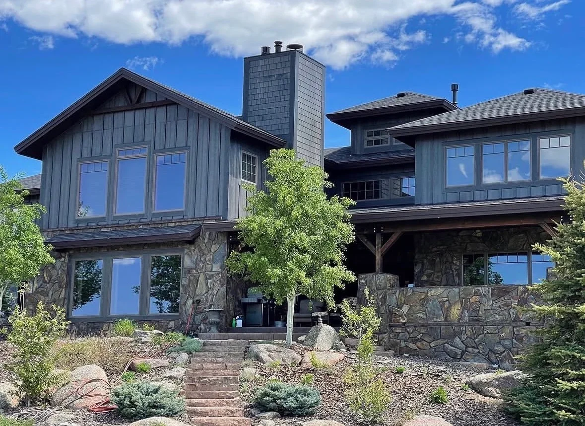 Modern home with charcoal metal siding, stone veneer, and large windows
