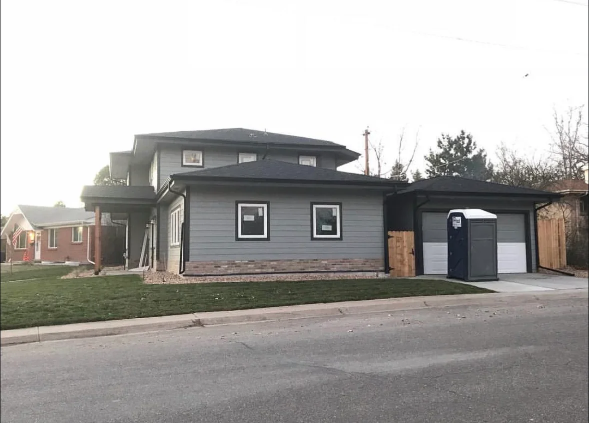Two-story home with gray fiber cement siding, black trim, and updated garage doors