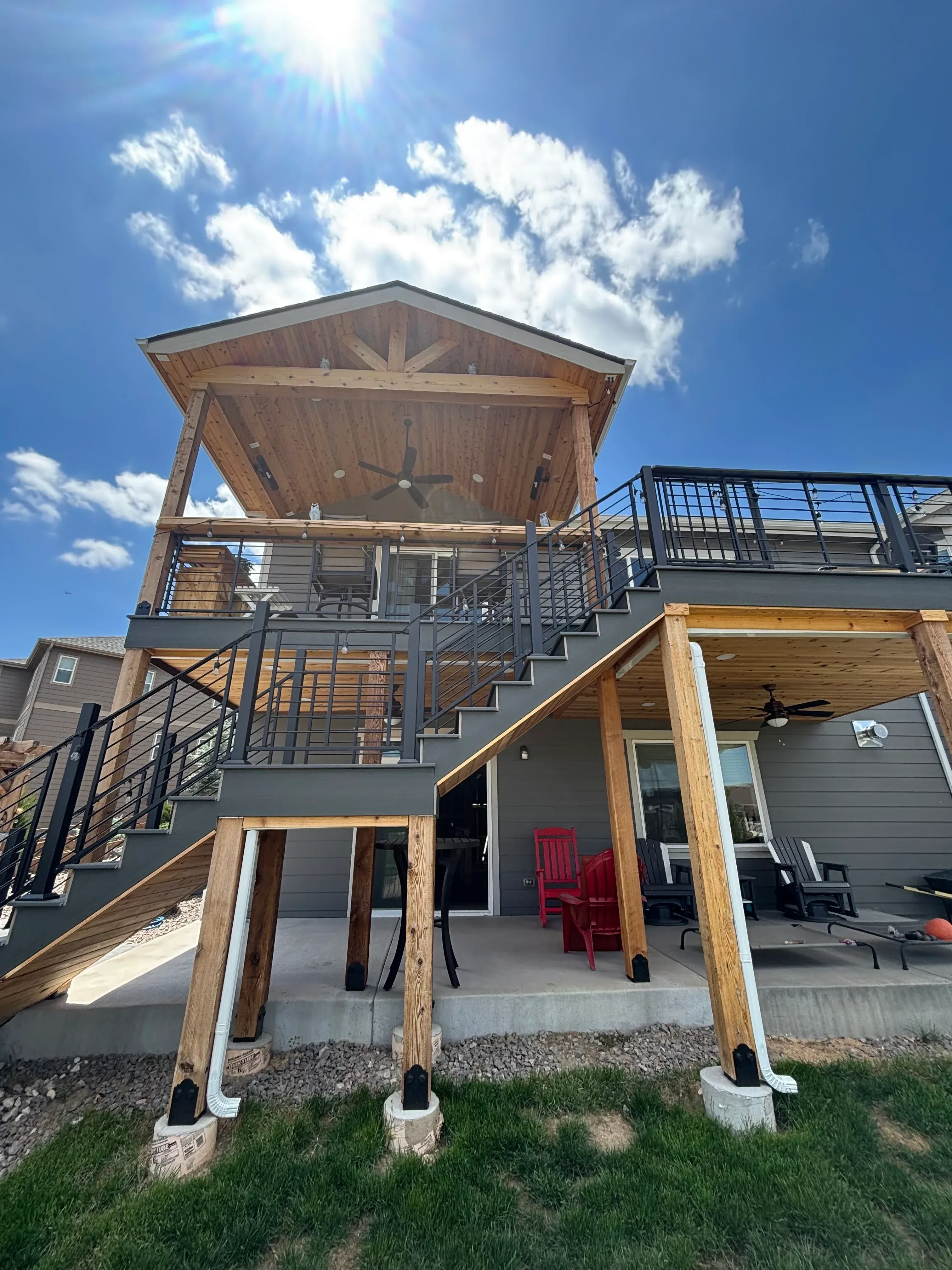 Multi-level deck with wood beams, metal cable railing, and exterior stairs