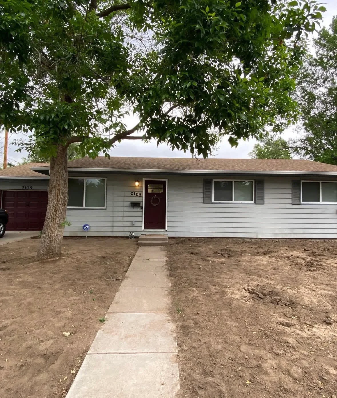 Light gray fiber cement siding with burgundy door and updated window frames on ranch home