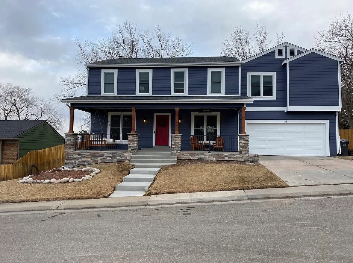 Navy blue two-story home with new front porch, stone pillars, wooden columns, and concrete steps