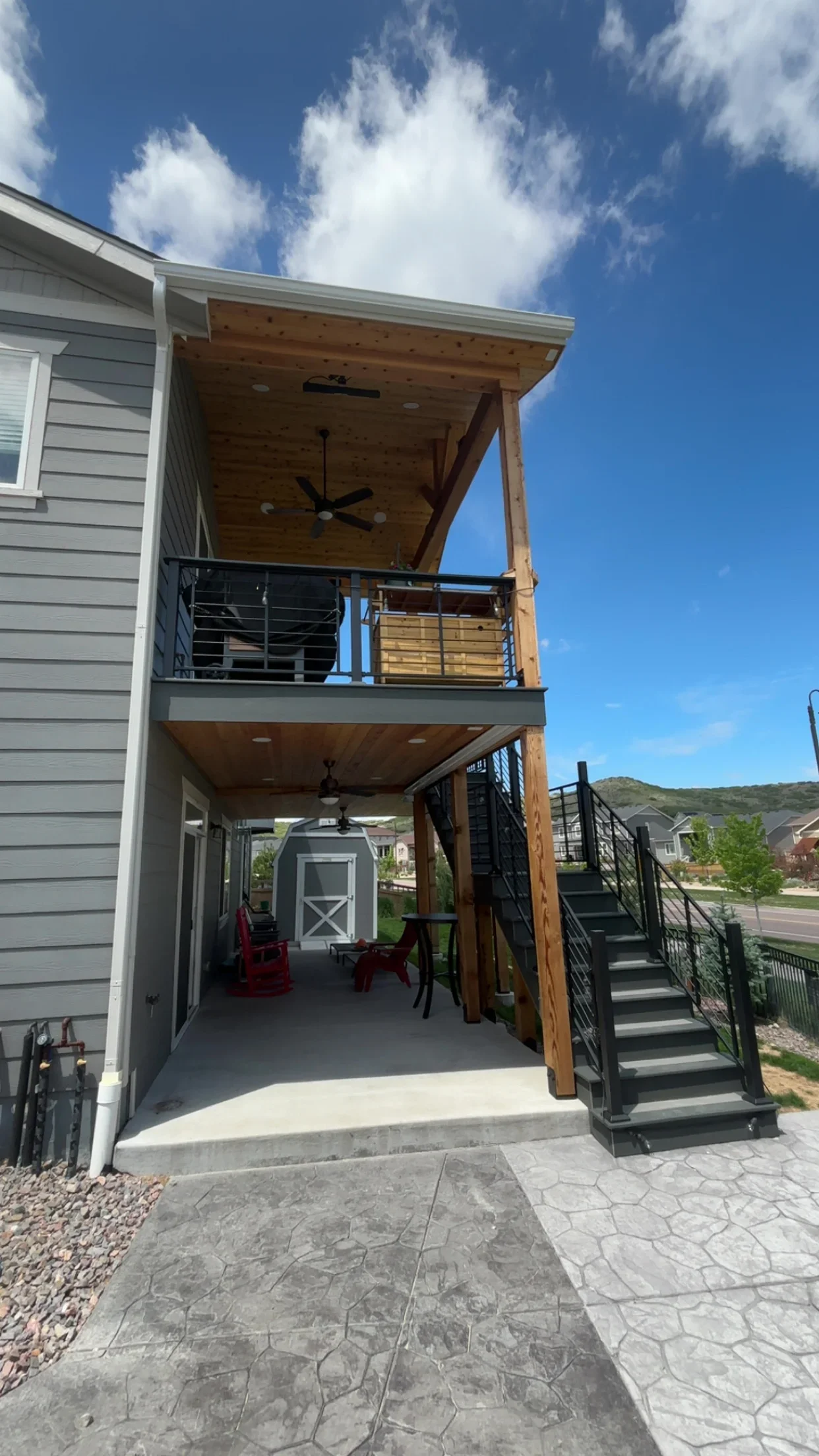 Two-story timber deck with composite decking, black cable railings, and stamped concrete patio