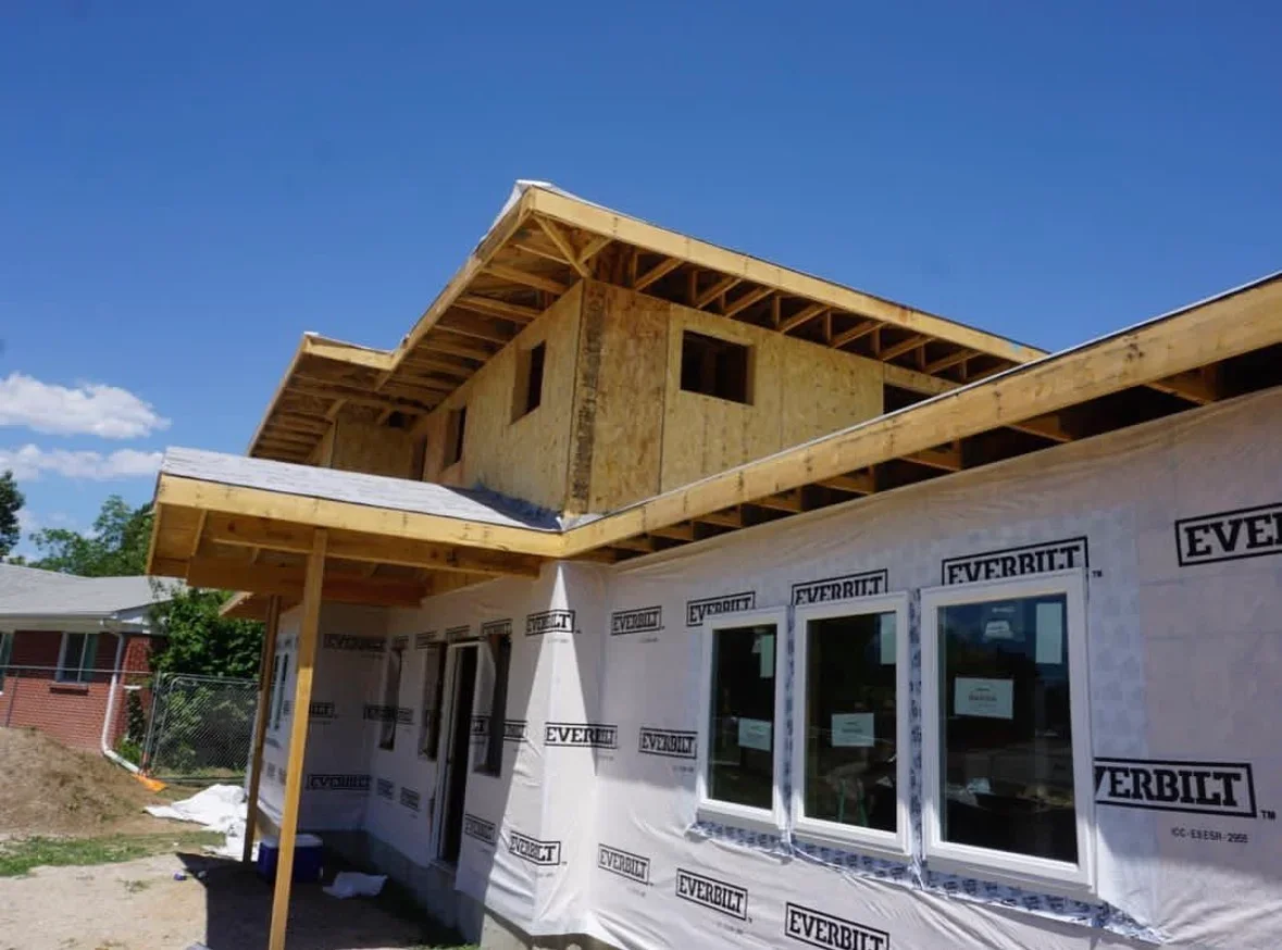 Wood-framed covered patio with exposed beams and large windows under construction