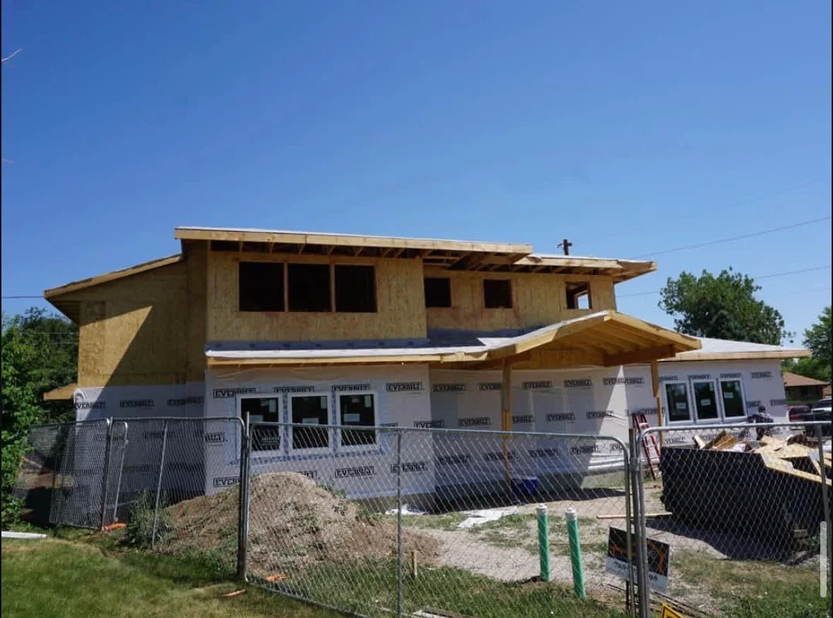 Residential home framing with OSB sheathing, house wrap, and metal deck railing during construction
