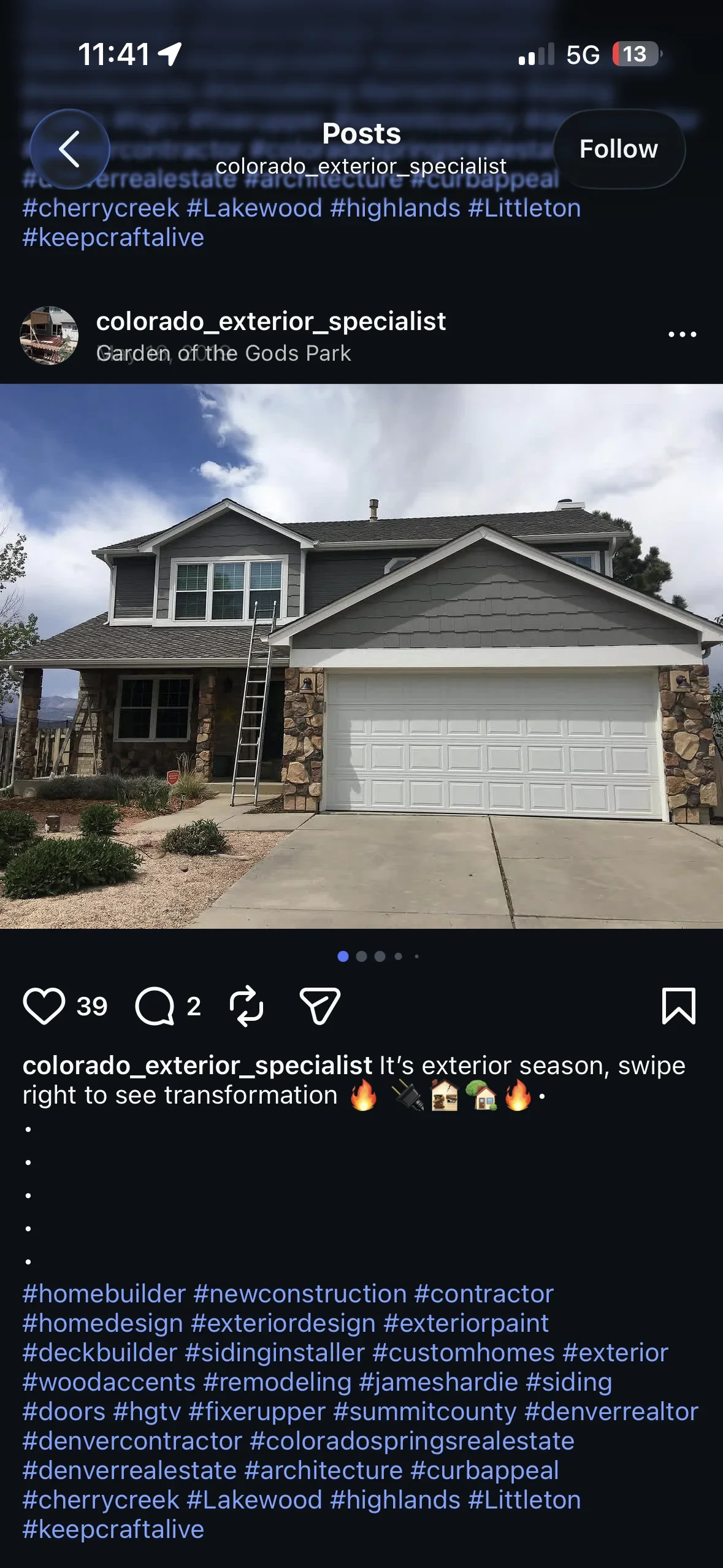 Two-story home with dark gray siding, white trim, stone veneer, and white garage door
