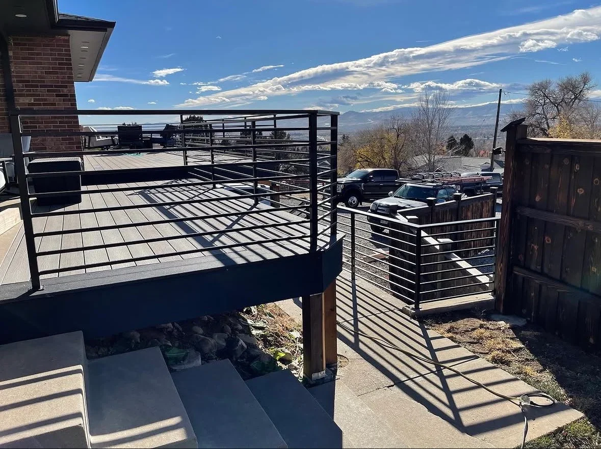 Elevated composite deck with black metal railings, horizontal balusters, and gate system