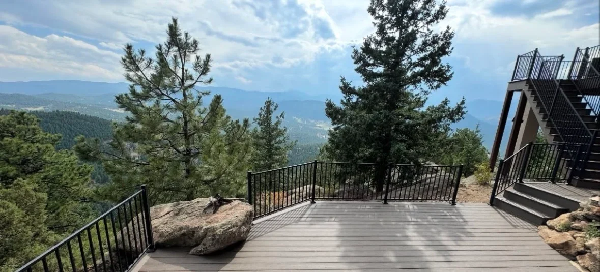 Composite deck with black metal railing overlooking forested mountain valley