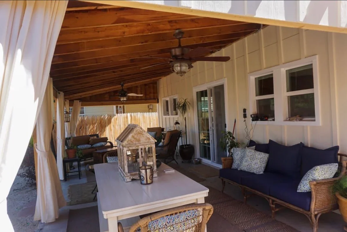 Covered patio with wood ceiling beams, ceiling fans, concrete floor, and white railings