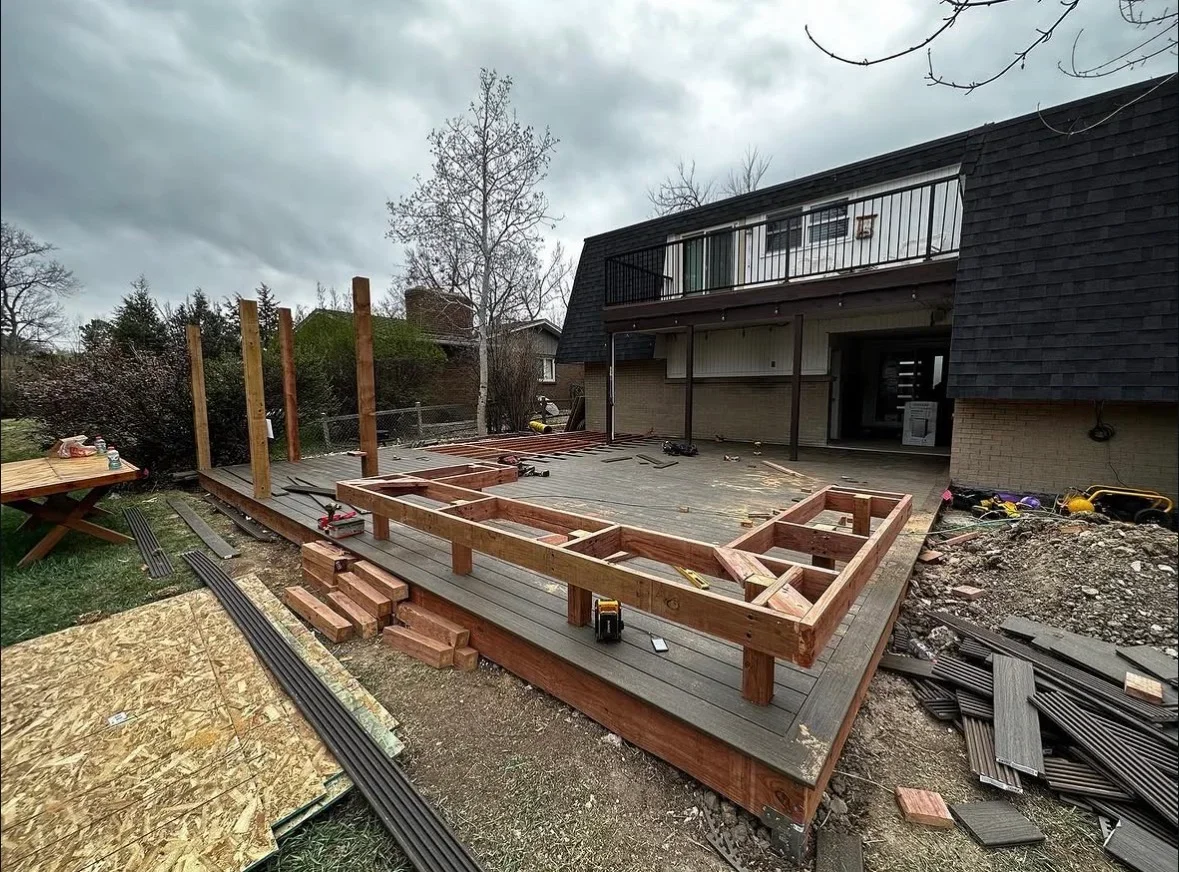 Deck framing with pressure-treated lumber, built-in planters, and tiered construction during installation