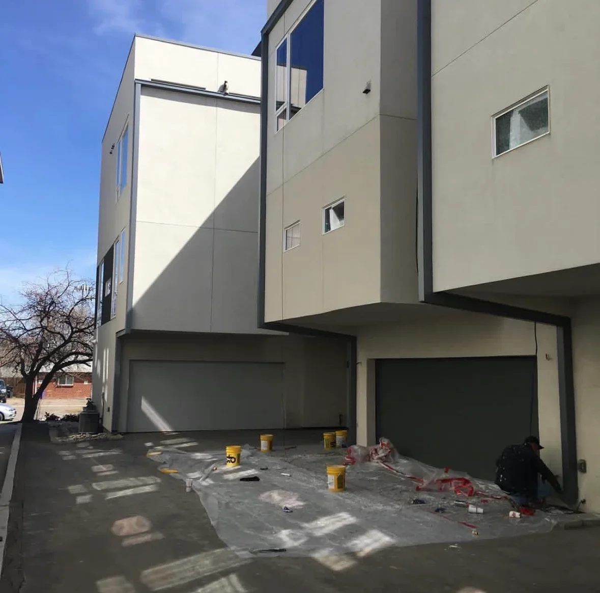 Concrete driveway and patio base with modern home facade and dark garage doors