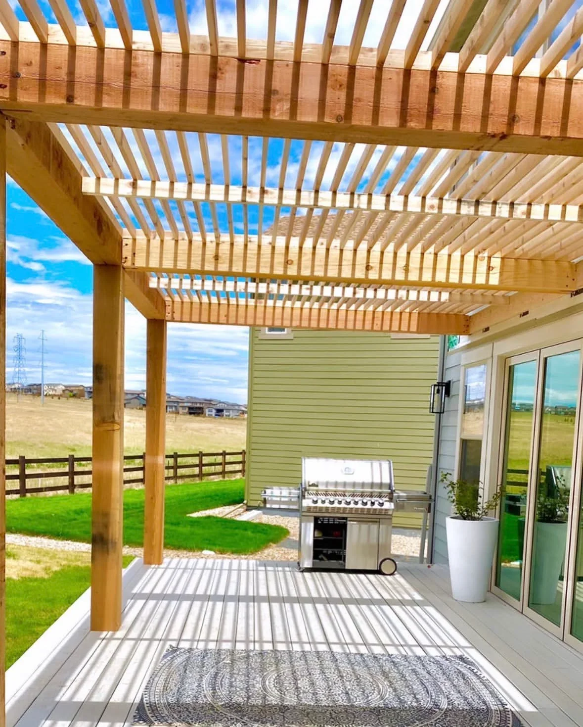Wood pergola deck with composite decking, built-in grill, and slatted roof design