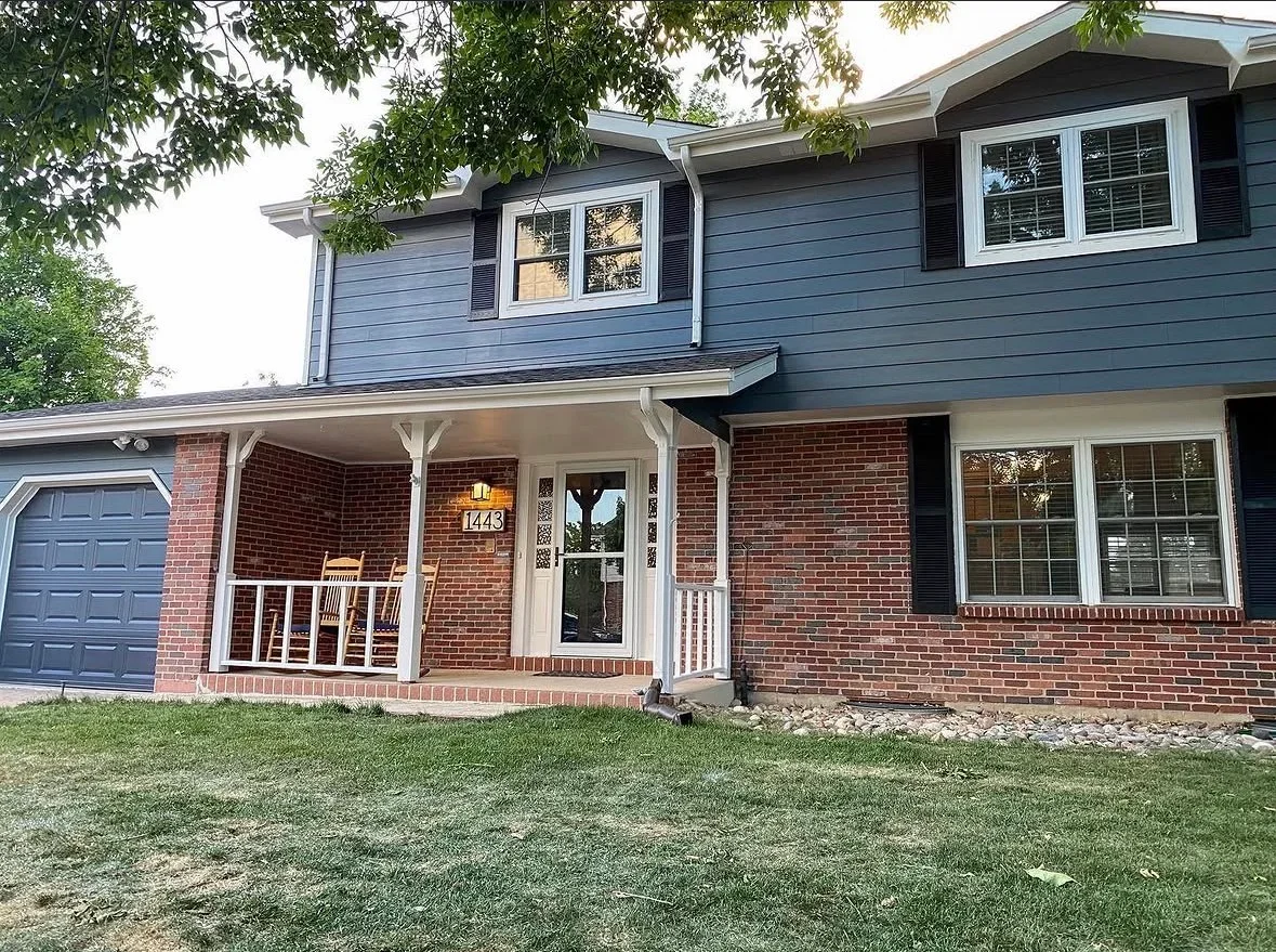 Front porch deck with white posts and railings on brick home with upper-level deck