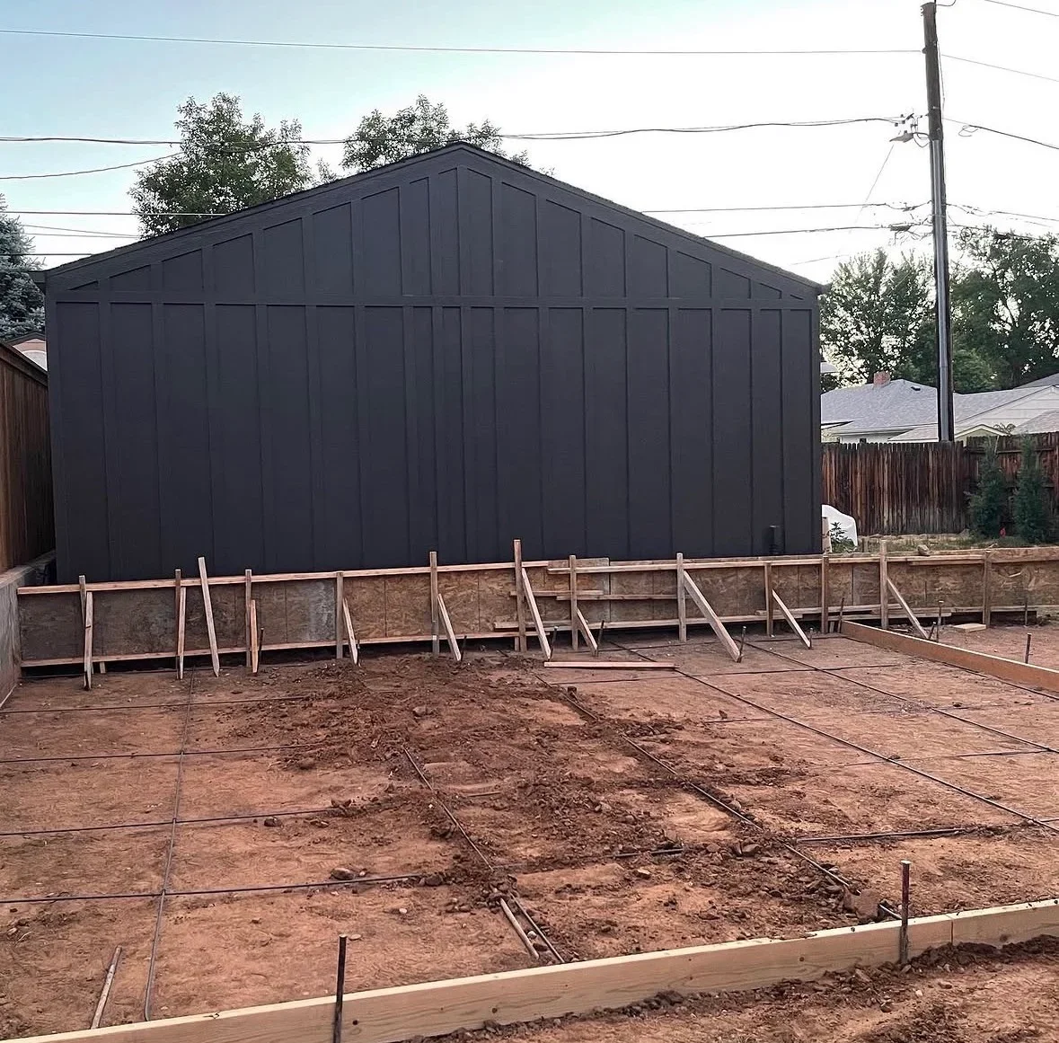 Black barn structure on new concrete foundation with wooden bracing and drainage layout