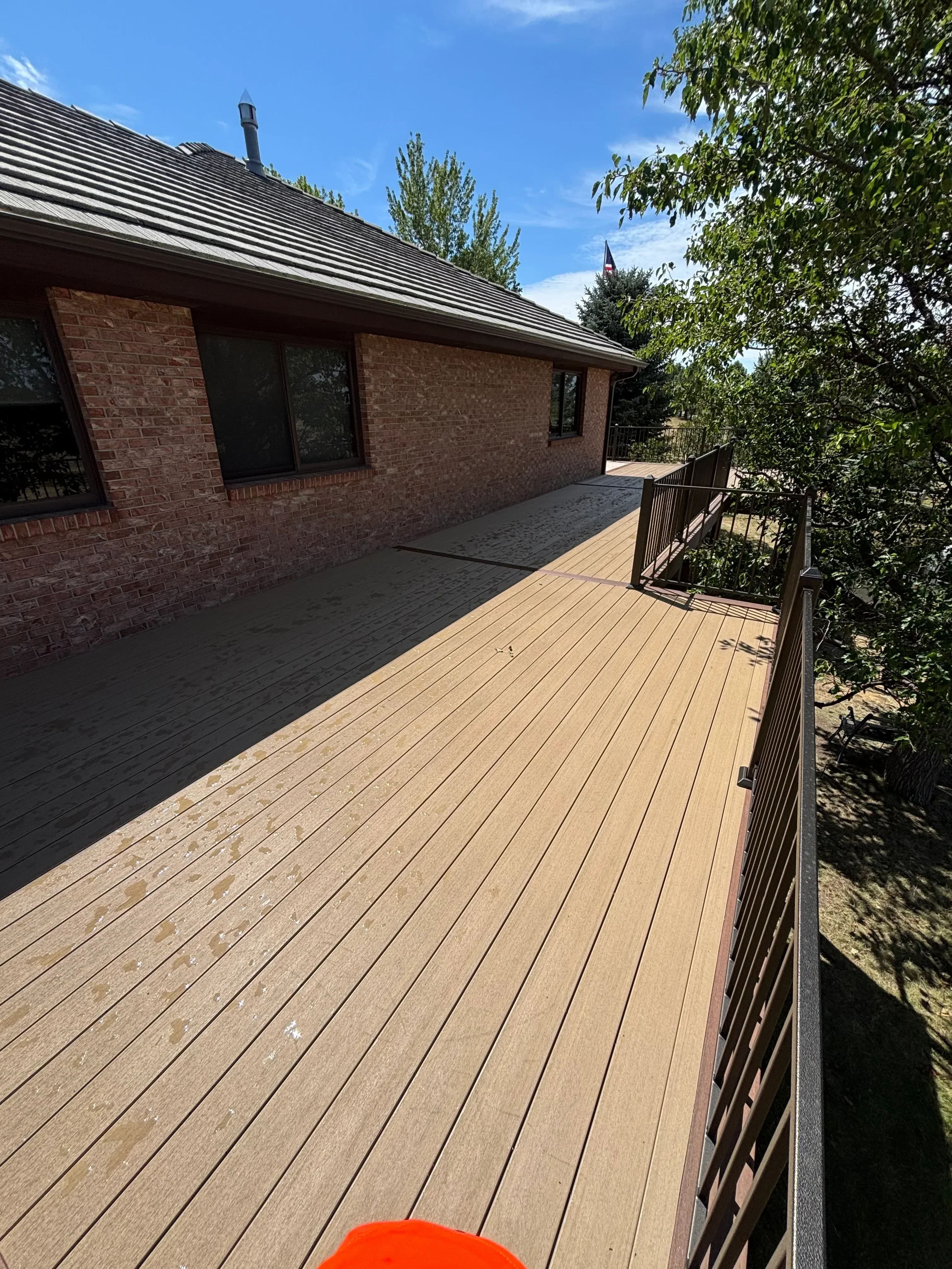 Composite deck with horizontal boards, metal railing, and brick home exterior
