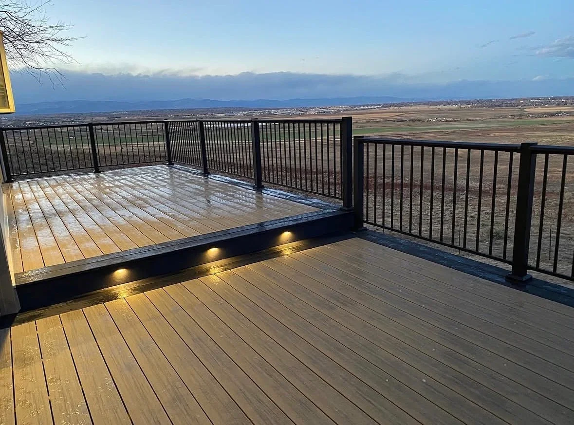 Composite deck with LED lighting, black metal railings, and multi-level design overlooking valley landscape