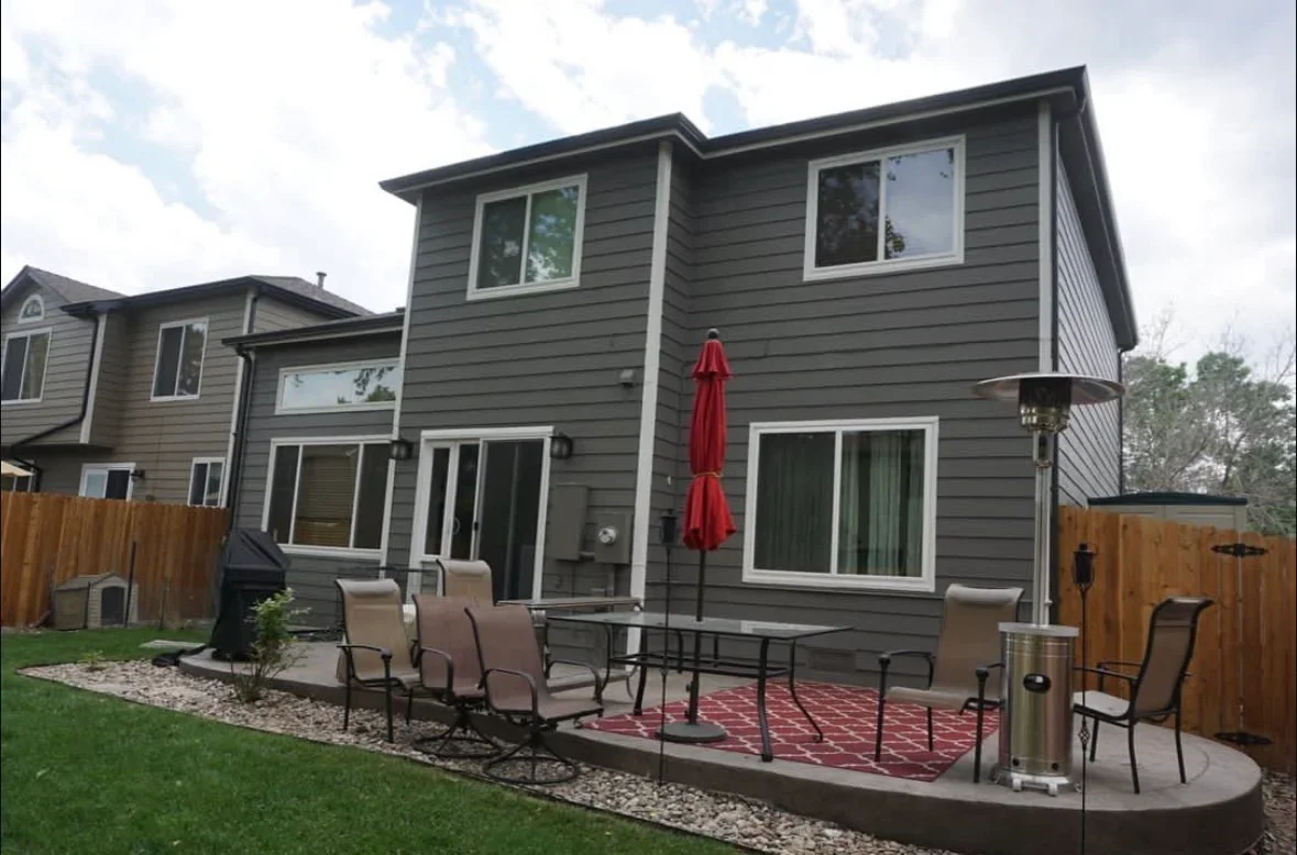 Curved concrete patio with seating area, gravel border, and wooden fence