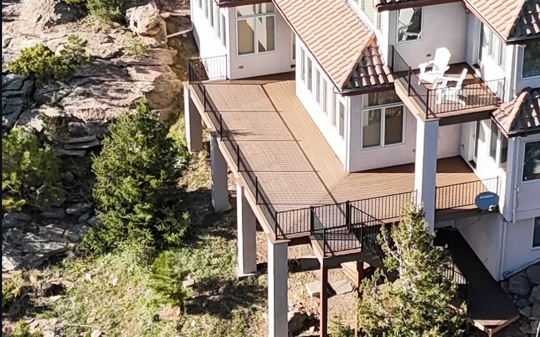 Tan composite multi-level deck with black metal railings and stairs on residential home