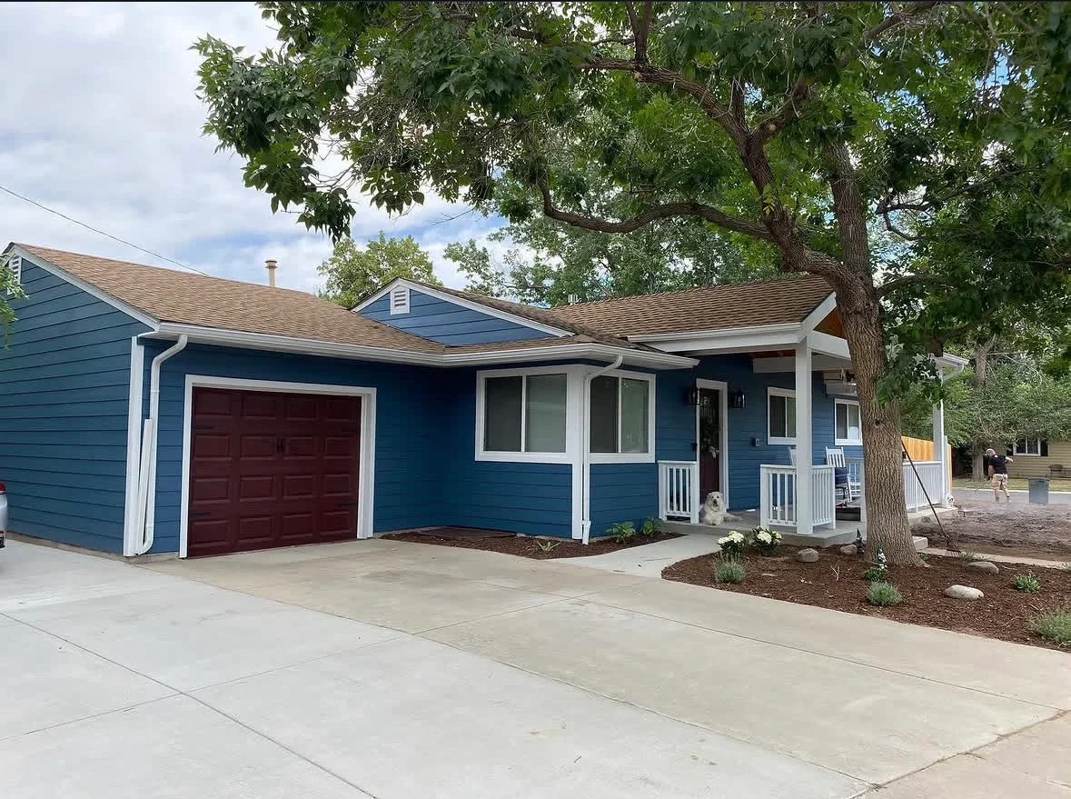 Concrete driveway and walkway with finished edges, mulch landscaping, blue siding home