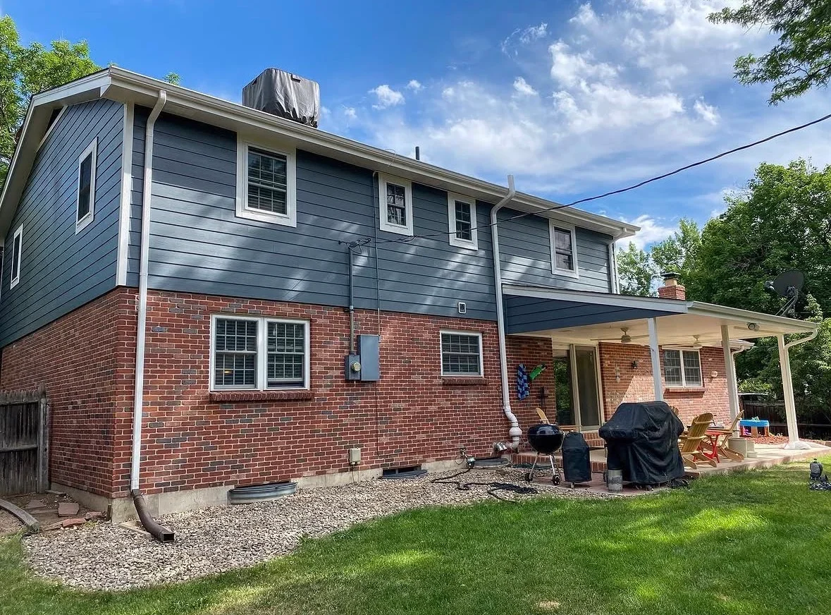 Brick home with new white-columned covered patio, updated siding, and window trim