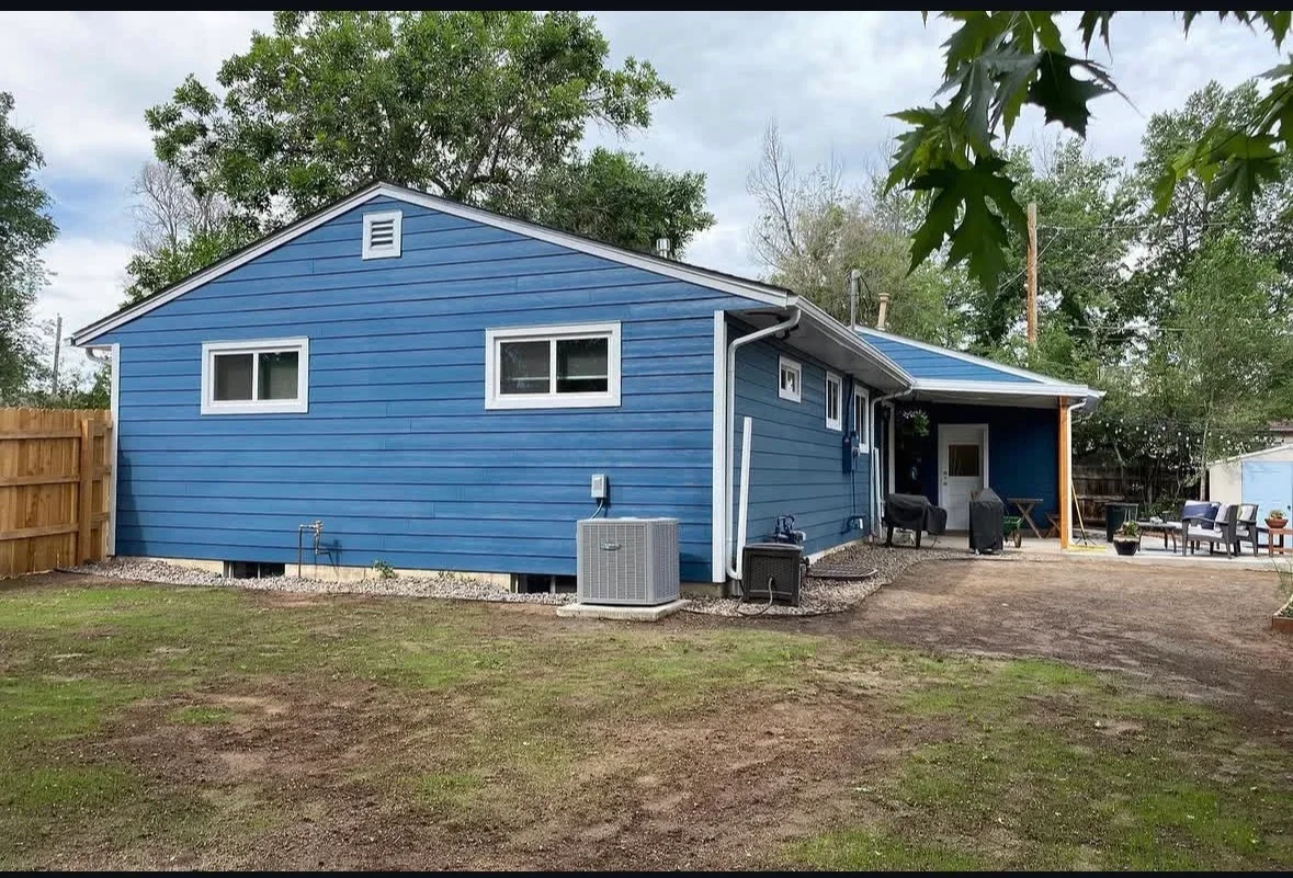 Blue horizontal lap siding with white trim, new windows, and covered patio extension on residential home