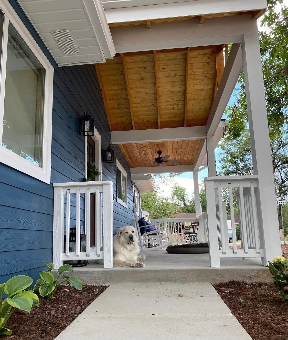 Covered patio with white columns, exposed wood beams, and ceiling fan over concrete pad