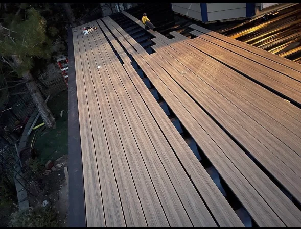 A repaired residential deck in Littleton, Colorado with replaced boards, tightened railings, and a freshly sealed surface. The deck is attached to a single-family home with a sloped backyard typical of the Littleton area.