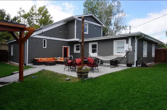 A Littleton, Colorado home with newly installed exterior siding, clean trim, and updated corner boards visible along the front and side elevations. Fresh flashing and tight panel seams show a complete exterior replacement on a mid-century residential property.
