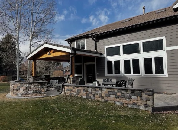 Newly installed natural stone retaining wall and walkway at a Littleton, Colorado residential property. The stonework runs along a sloped yard with a compacted base visible at the wall footing.